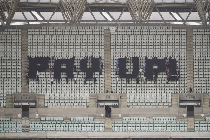 Activists with signs spell out "pay up" for climate finance in the Baku Olympic Stadium during COP29.