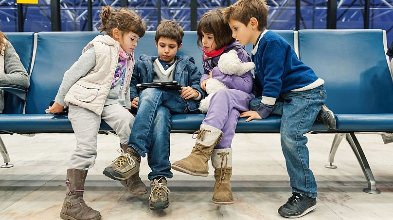 Children wait for a flight inside Lisbon airport at night