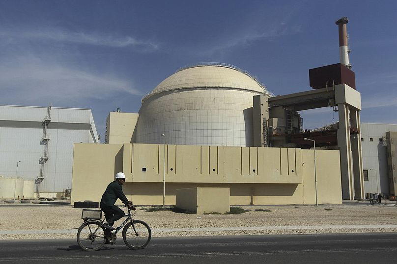 A worker rides a bike in front of the reactor building of the Bushehr nuclear power plant, 26 October, 2010