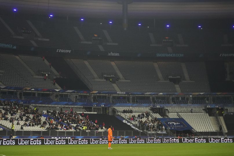 Le gardien français Mike Maignan devant un stade aux tribunes quasi vides. 