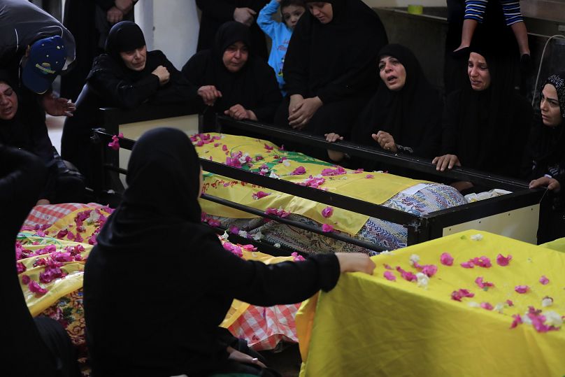 Las mujeres lloran junto a los cuerpos de las víctimas envueltos en banderas de Hezbolá, que murieron en un ataque aéreo israelí, durante un funeral masivo en el sur de Líbano