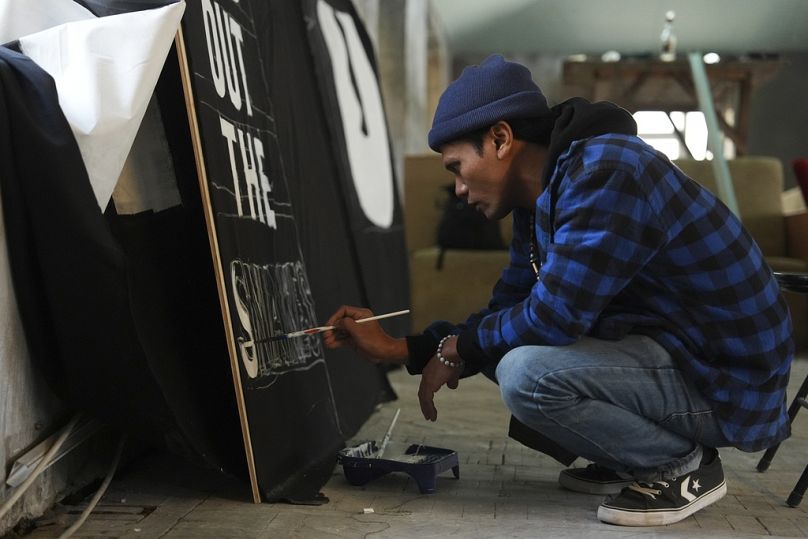 Shaq Koyok, of Malaysia, paints a sign ahead of a demonstration during COP29.