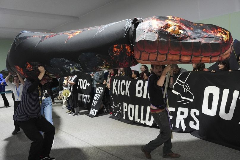 Kevin Buckland, right, and other activists participate in a demonstration against fossil fuels called weed out the snakes at COP29.