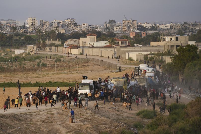 Palestinians storm trucks loaded with humanitarian aid brought in through a new US-built pier in central Gaza, 18 May, 2024