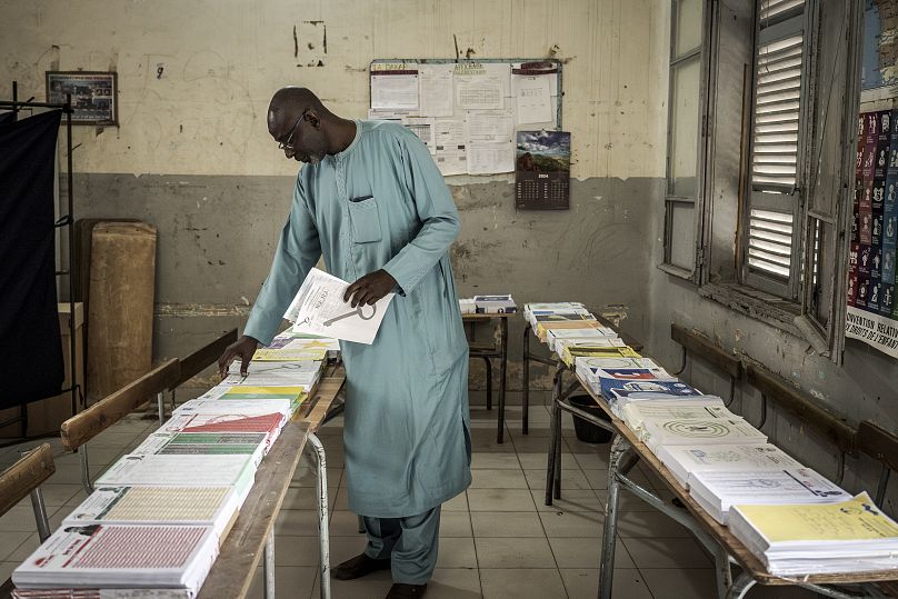 Un homme récupère les cartes d'électeur posées sur une table avant de voter pour les élections législatives dans un bureau de vote à Dakar, au Sénégal, l7 novembre 2024