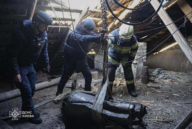 Emergency services personnel remove part of a Russian missile that hit an apartment house during massive missile attack in Kyiv, Ukraine, Sunday, Nov. 17, 2024.