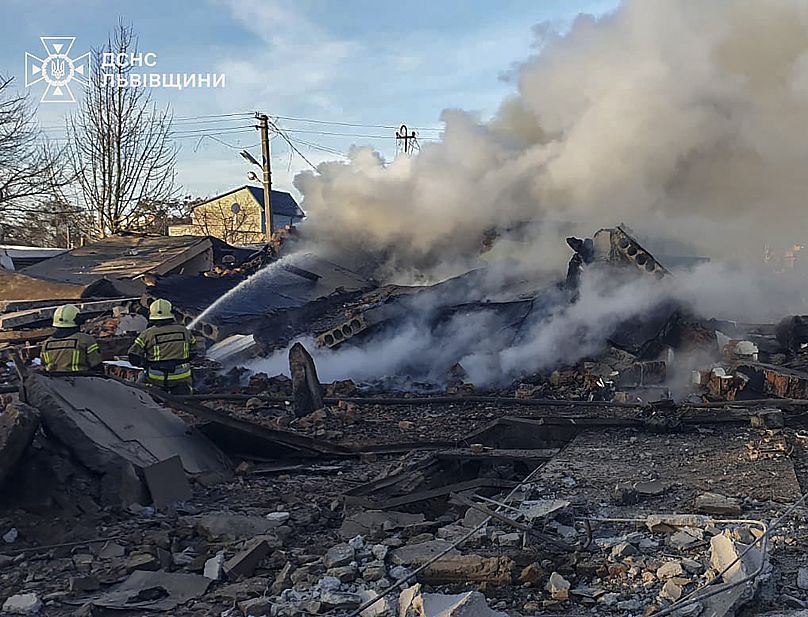 Bomberos apagando el fuego tras el impacto de un misil en una casa