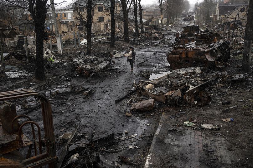 Une femme marche au milieu de chars russes détruits à Bucha, dans la banlieue de Kyiv, le 3 avril 2022.