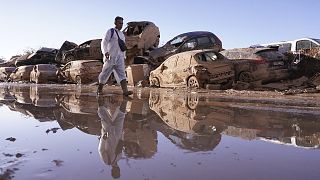 Un uomo passa davanti a delle auto accatastate dopo le inondazioni di Catarroja, che hanno causato centinaia di morti e dispersi nella regione di Valencia, in Spagna, martedì 12 novembre 2024.