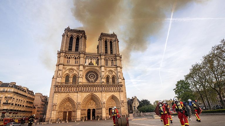 This photo provided Tuesday April 16, 2019 by the Paris Fire Brigade shows fire fighters heading to the burning Notre Dame cathedral, Monday April 15, 2019. 