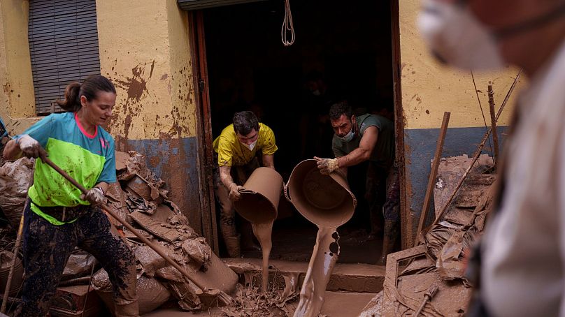 La gente limpia el barro de una casa afectada por las inundaciones, en Algemesí, España.