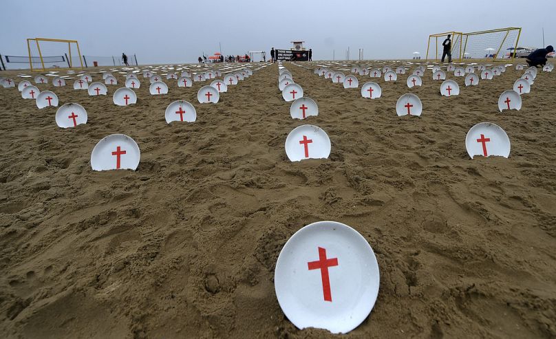 Plates marked with crosses, symbolizing people suffering from hunger worldwide, are scattered at Copacabana Beach during a protest in Rio, Saturday, Nov. 16, 2024,