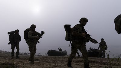 krainian servicemen walk on the shore of Dnipro river