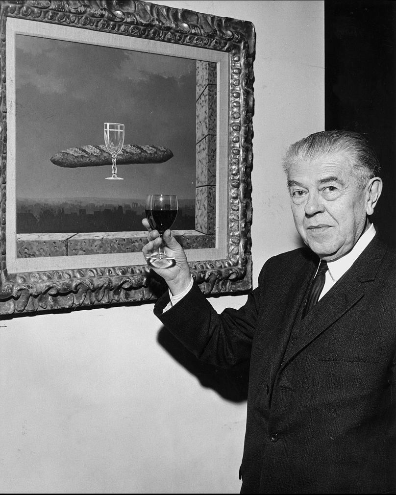 Nesta fotografia sem data de 1965, René Magritte brinda ao seu quadro “Força da Circunstância”, de 1958, na casa dos Menil em Houston, Texas