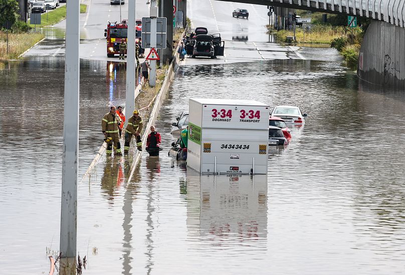 Firefighters work at a flooded road in Copenhagen.