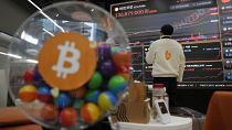 File photo - An employee watches an electronic signboard displaying the prices of Bitcoin 