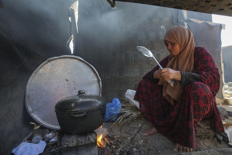 Yasmin Eid cozinha na tenda da família num campo de refugiados em Deir al-Balah, Faixa de Gaza, terça-feira, 19 de novembro de 2024.