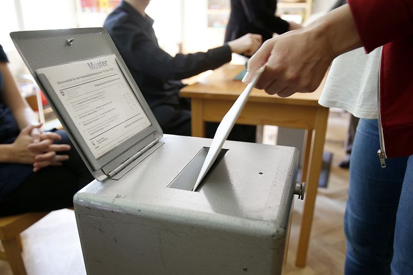 A Swiss voter casts their referendum ballot at a polling station in Bern, 18 May, 2014