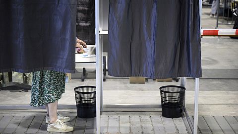 Person stands at ballot box. 