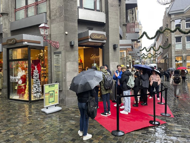 Menschen stehen vor einem Lindt-Schokoladengeschäft Schlange, um limitierte Tafeln "Dubai Chocolate" zu kaufen, in Aachen, Deutschland, Donnerstag, 14. November 2024.