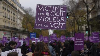 A protestor holds a placard reading "Victim we believe you. Rapist we see you" during a march for the International Day for the Elimination of Violence Against Women in Paris.