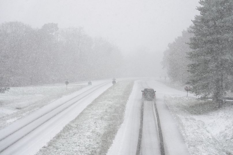 A car drives along a snow-covered road in the forest of Fontainebleau, south of Paris