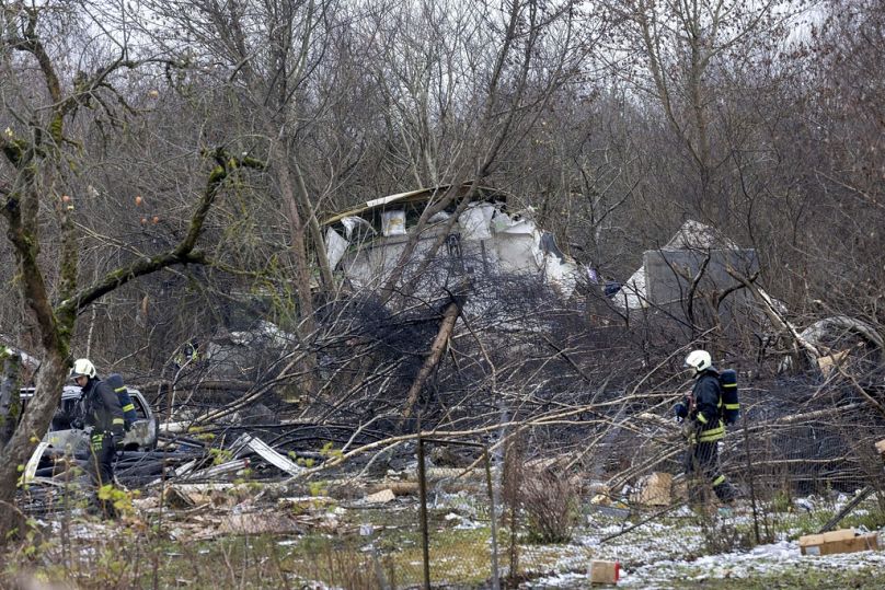 Funcionários do Ministério das Emergências da Lituânia trabalham no local onde um avião de carga da DHL se despenhou contra uma casa perto de Vilnius, Lituânia