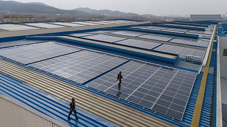 Workers cleaning solar panels work on the rooftop of the factory of energy equipment manufacture Iraeta on the outskirts of Jinan in eastern China.