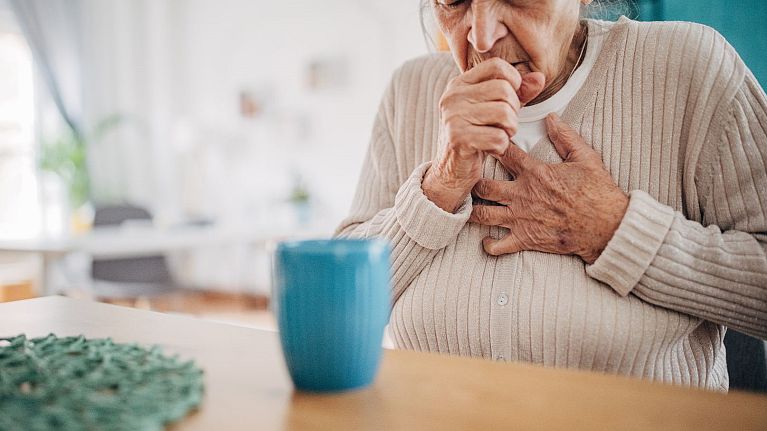 An older woman coughs.