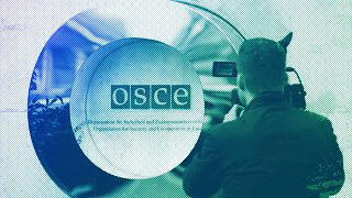 A cameraman films the OSCE logo outside the venue of an OSCE Parliamentary Assembly, in Vienna, February 2023