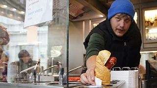 A vendor serves a hot dog at a traditional sausage stand 