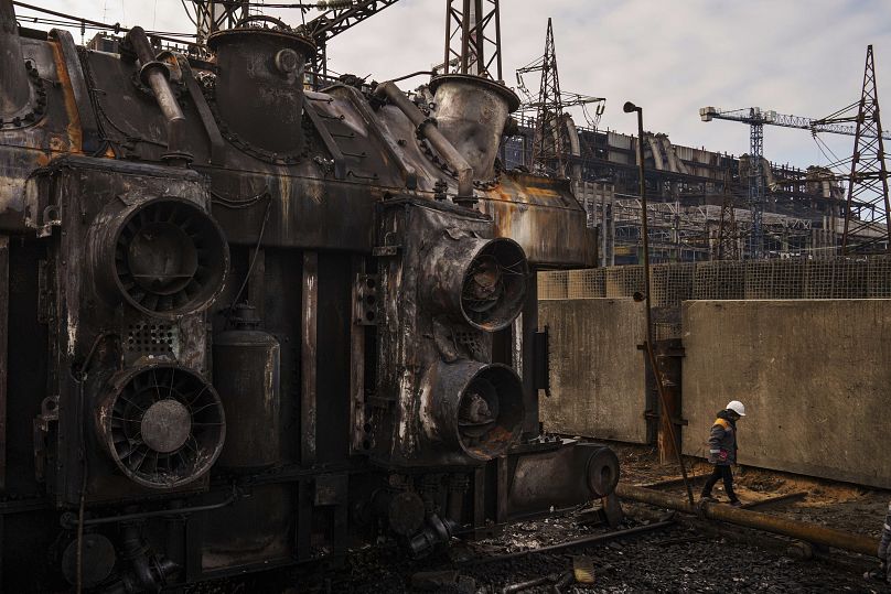 Un lavoratore cammina davanti a un trasformatore che è stato distrutto dopo un recente attacco missilistico russo alla centrale elettrica della DTEK in Ucraina