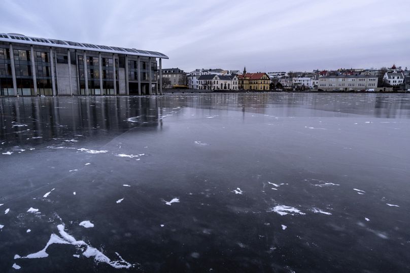 Vista de Tjörnin, a lagoa da cidade completamente congelada, com a câmara municipal à esquerda e o centro de Reiquiavique ao fundo, sexta-feira, 29 de novembro de 2024. (AP Ph