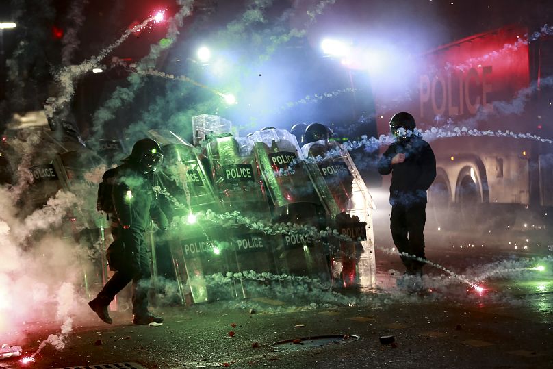 Des manifestants lancent des feux d'artifice sur des policiers devant le bâtiment du parlement à Tbilissi, en Géorgie, tôt le samedi 30 novembre 2024.