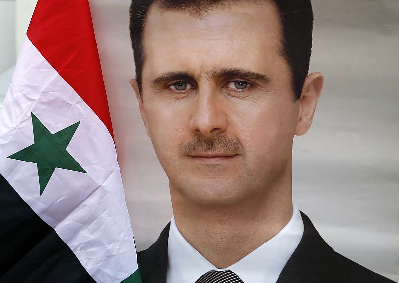 Un drapeau national syrien et une photo du président Bachar al-Assad lors d'une manifestation devant l'ambassade de Syrie à Belgrade, en Serbie, le dimanche 15 avril 2018.