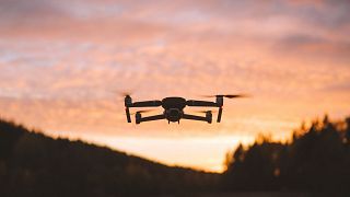 A drone flying in the sky at sunset