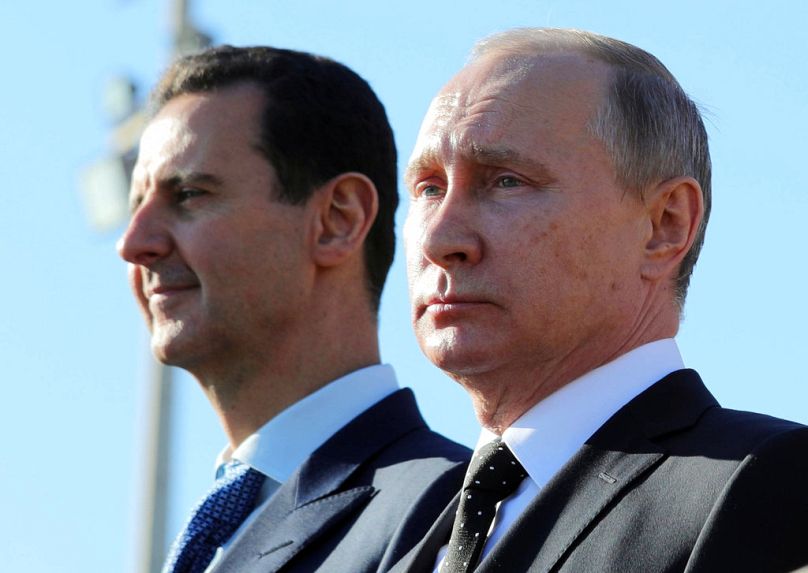 FILE - Russian President Vladimir Putin, right, and Syrian President Bashar al-Assad watching troops march at the Hemeimeem air base in Syria in 2017.