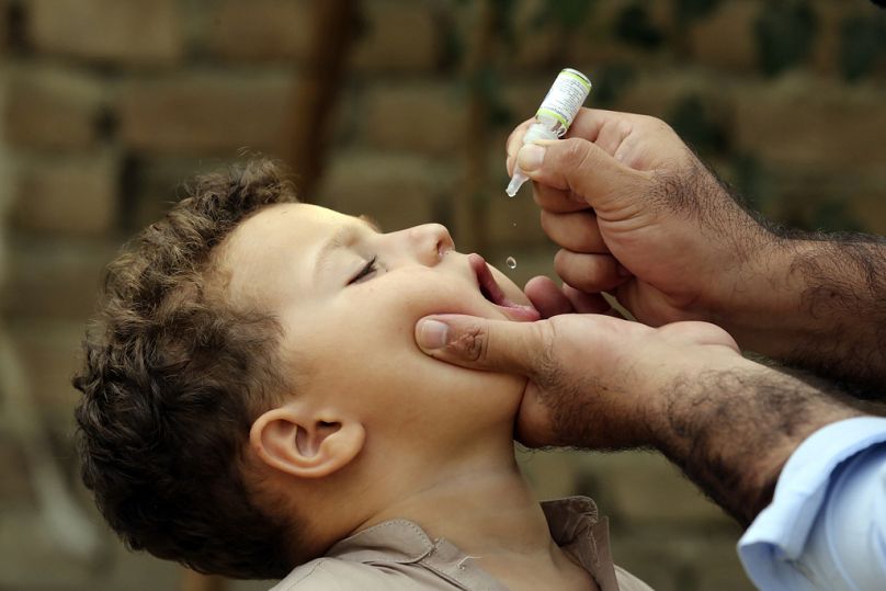أحد العاملين في مجال الصحة يعطي لقاح شلل الأطفال لطفل في حي من أحياء جلال آباد شرق كابول، أفغانستان، يوم الثلاثاء 29 أكتوبر/تشرين أول 2024.