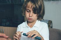 A child uses an insulin pen at the doctor's office.