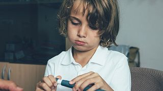 A child uses an insulin pen at the doctor's office.