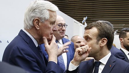 French President Emmanuel Macron, right, whispers to European Union chief Brexit negotiator Michel Barnier at the International Agriculture Fair, in Paris, on Feb 23, 2019.