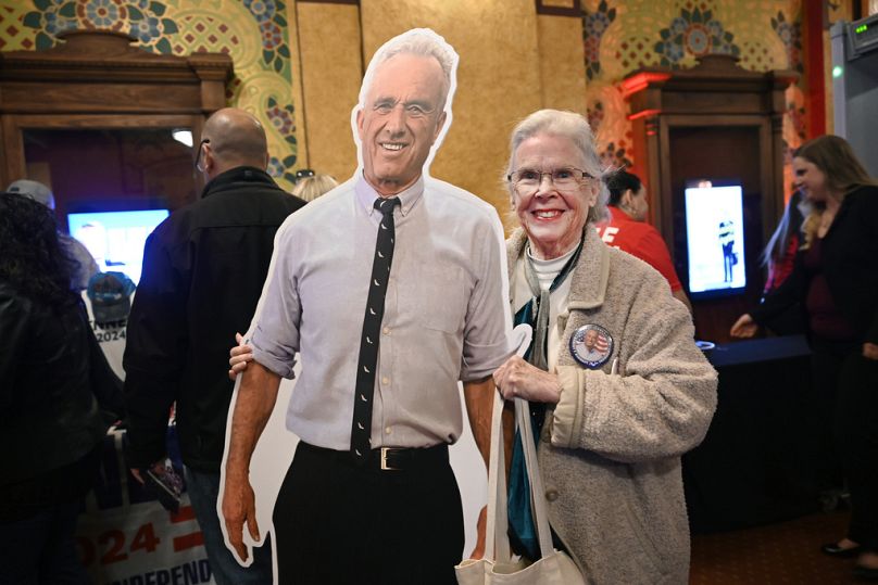 A woman poses for photos with her cutout of Independent presidential candidate Robert F Kennedy Jr in Royal Oak, MI, 21 April 2024