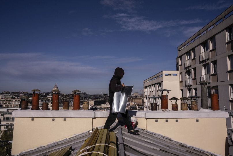 Um telhador transporta chapas de zinco para telhados em Paris