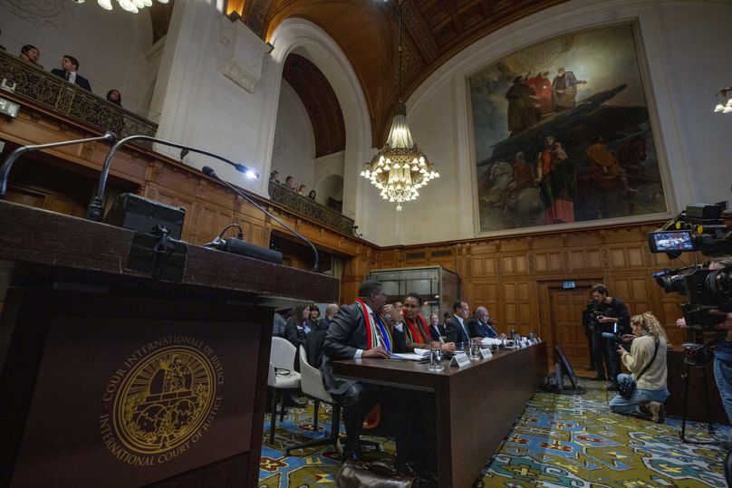 Vanuatu's, rear, and South Africa's delegation, left, wait as the International Court of Justice in The Hague, Netherlands, opens hearings.