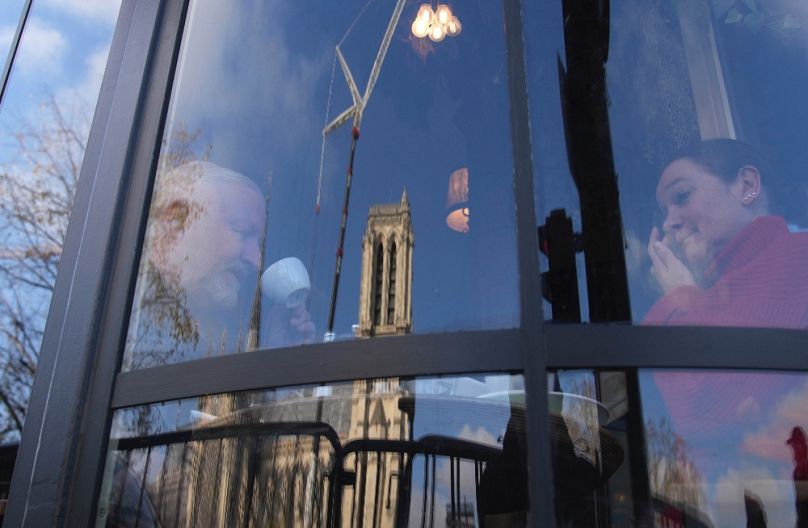 A felújított Notre-Dame egy kávézó ablakán tükröződik, 2024. december 4-én