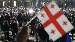 A demonstrator holds a Georgian flag during a rally to protest against the government's decision to suspend EU negotiations in Tbilisi, 5 December, 2024