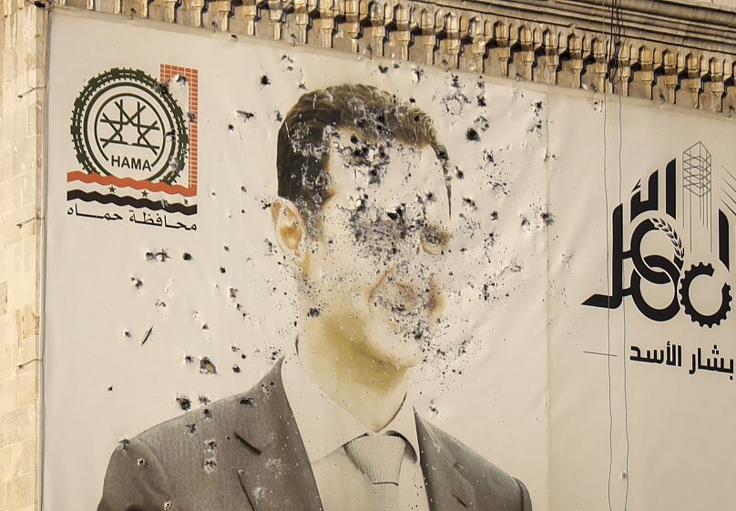 An image of Syrian President Bashar Assad, riddled with bullets, is seen on the facade of the provincial government office in Hama, 6 December, 2024