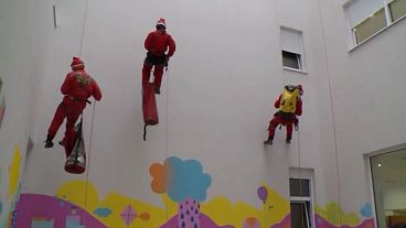 Members of the Mountain Rescue Service, dressed as Father Christmas, descend along the university clinic in Mostar, Bosnia-Herzegovina, 06.12.2024
