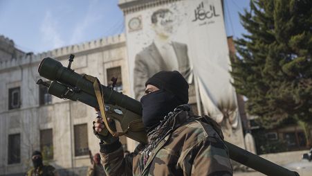 A Syrian opposition fighter holds a rocket launcher in front of the provincial government office in Hama, 6 December, 2024