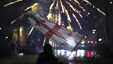 A demonstrator waves a Georgian flag during a protest in Tbilisi, 7 December, 2024